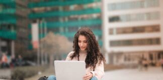 woman in pink sweater using laptop